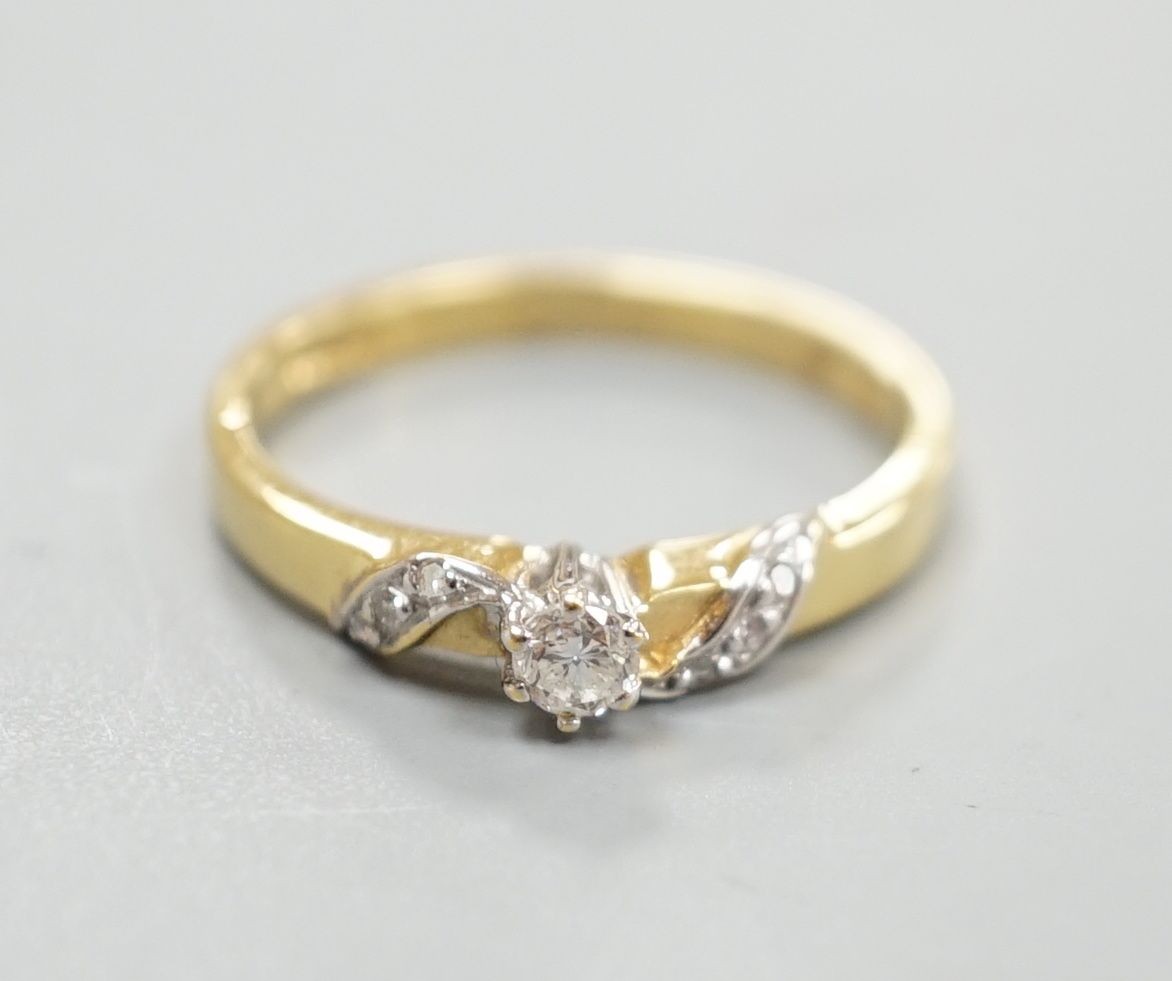 A modern 18ct gold and single stone diamond ring, with diamond chip set 'crossover' shoulders, size M/N, gross weight 2.8 grams.